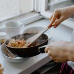 Person dishing out stir fry from pan