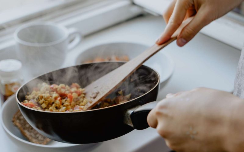 Person dishing out stir fry from pan